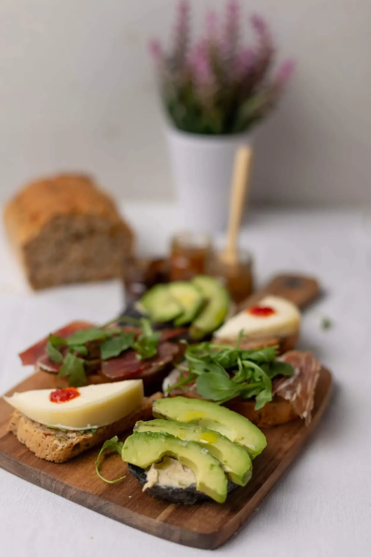 Tabla de quesos, mermeladas, frutos secos y panes artesanales sobre una superficie de madera