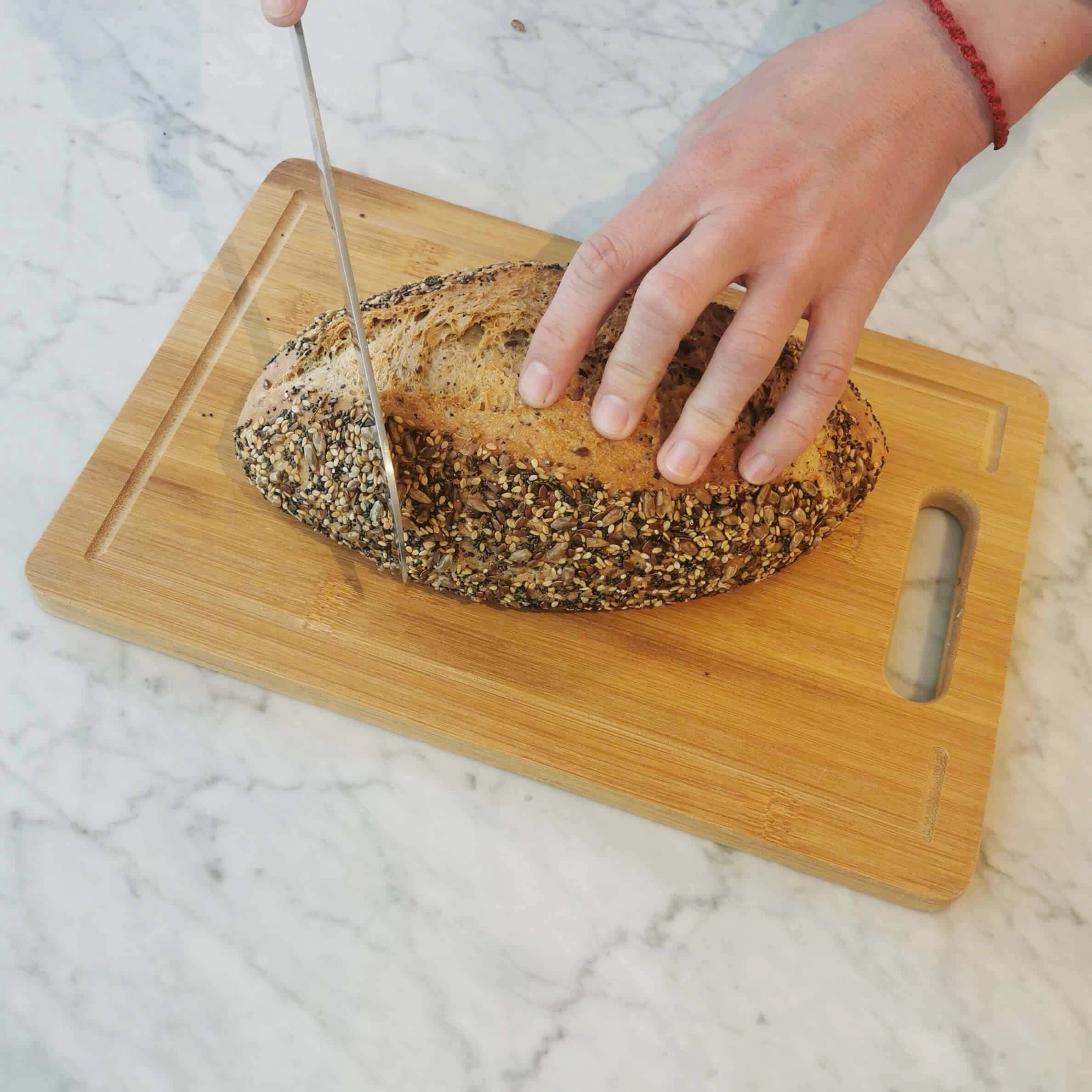 Pan de semillas siendo cortado en una tabla de madera