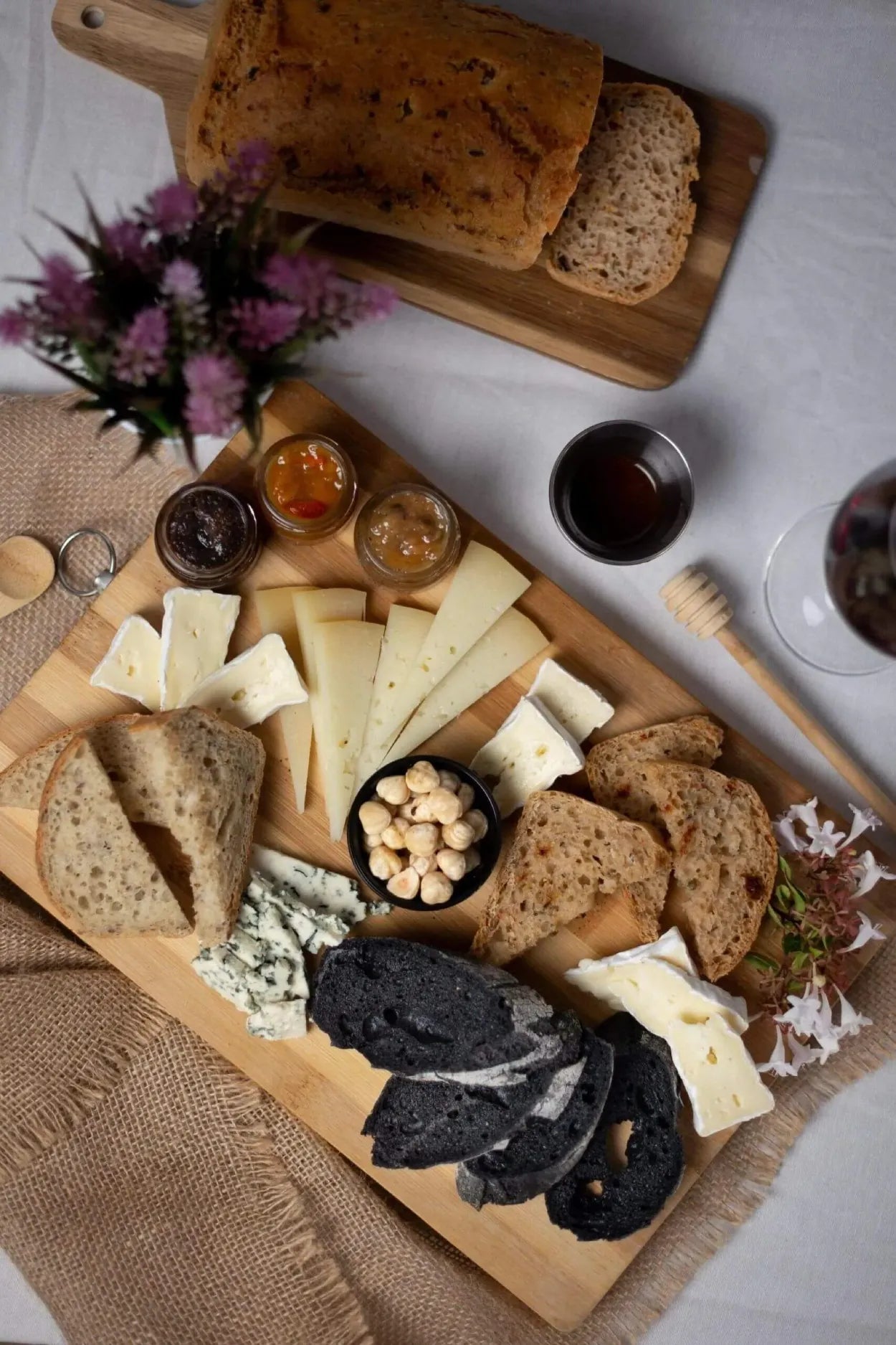 Tabla con tostadas de pan artesanal acompañadas de aguacate, queso, jamón y rúcula
